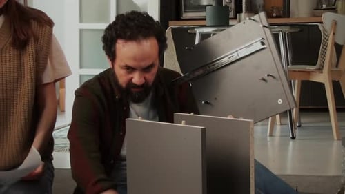 Busy Caucasian Couple Putting Together Parts of Flatpack Drawer