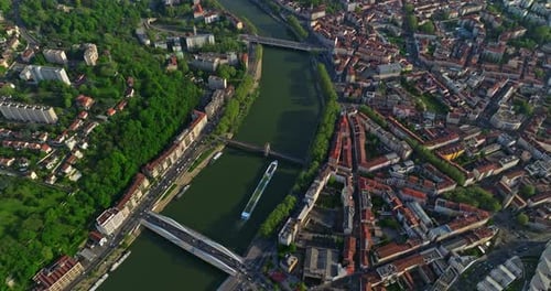 Drone de cima para baixo fotografado sobre a cidade ao pôr do sol ao longo de um rio azul Um navio turístico se move ao longo do rio Lyon