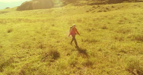 Flight Over Backpack Hiking Tourist Walking Across Green Mountain Field Huge Rural Valley at Summer