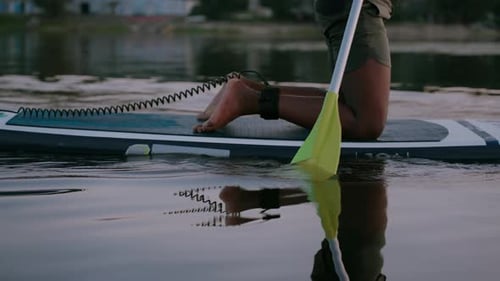 Muskulöser Mann rudert mit Paddel über den Abendsee