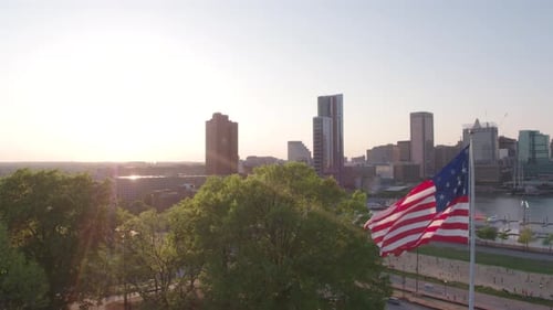 American Flag Waving over City Skyline at Sunset