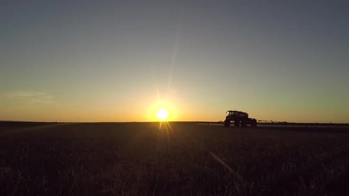 Tractor Working in Field at Sunset