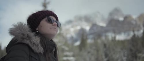 Close up of a woman with sunglasses against snowy mountains background in winter