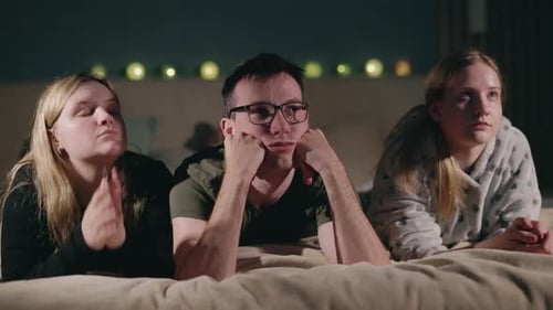 Young Adults Watching Something on a Bed at Night