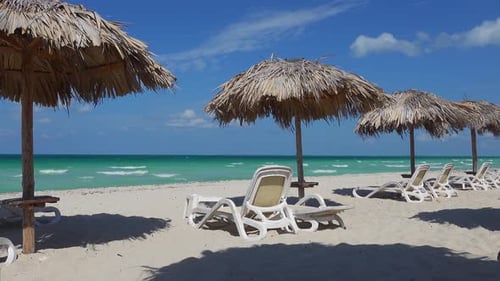 Sand beach, straw umbrellas in Varadero, Cuba, white sunbeds and blue ocean, wind and strong water w