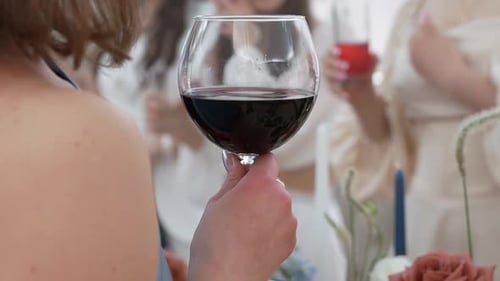Gros plan d'une fille tenant un verre de vin rouge dans un restaurant lors d'une fête