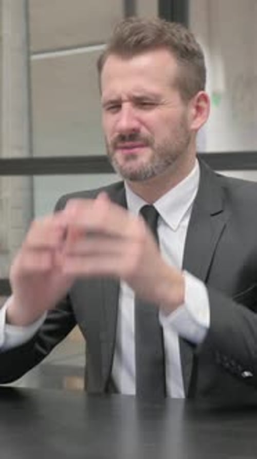Man in Suit Rubbing Temples at Desk