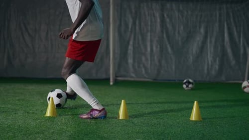 Entraînement au dribble d'un joueur de football, gros plan des pieds masculins et du ballon sur l'herbe