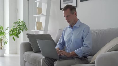 Man Working on Laptop While Sitting on Couch