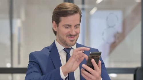 Excited Businessman Celebrating Success Using Mobile Phone