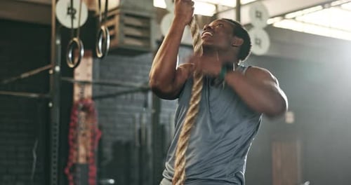 Fitness, gym and black man climbing rope for training, bodybuilder exercise and intense workout