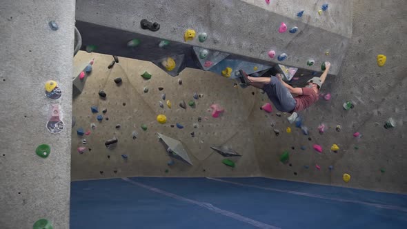 Inverted Rock climber climbing an indoor rock wall using athletic chalk ...