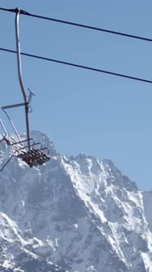 Cable Car on Background of Mountain Peaks and Blue Sky Creative Mountain Lift with Moving Empty