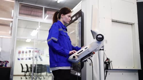 Young industrial worker operating cnc machine at metal machining industry