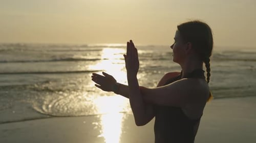 Woman Stretching at Golden Sunrise on Beach