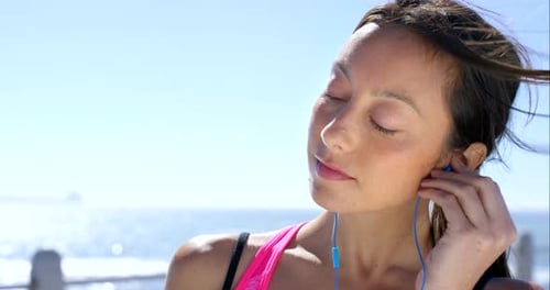 Woman Listening to Music by Ocean Using Phone