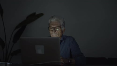 Senior Man Using Laptop Computer at Night