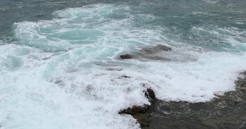 Sea water during a tide crashing strongly into a stony shore full of obstacles and hitting rocks the