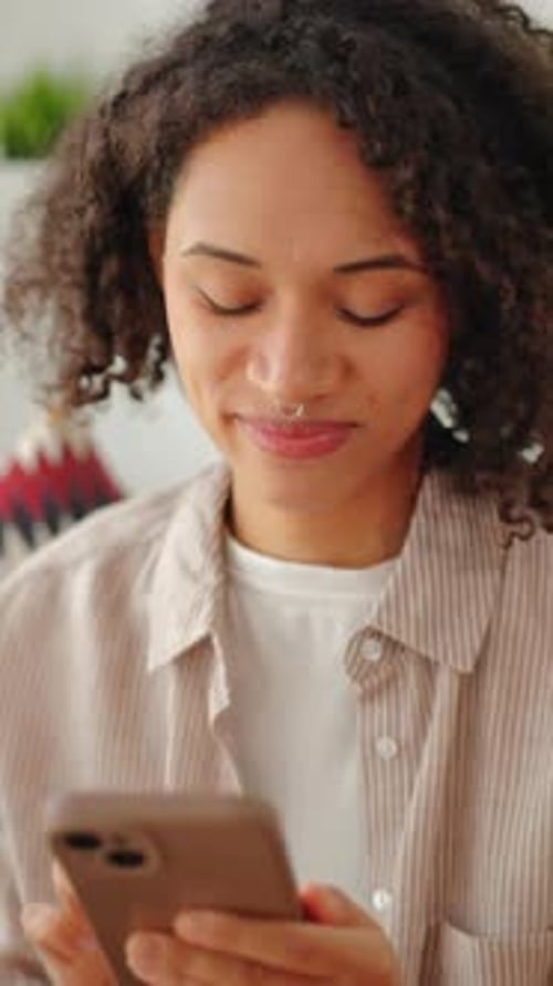 Young Woman Smiling and Typing on Mobile Phone