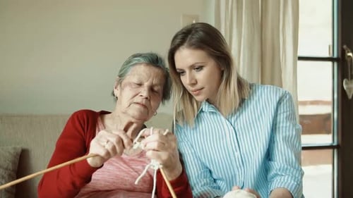 Senior Woman Knitting as Younger Woman Looks On