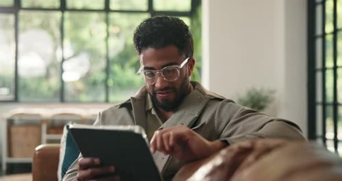 Man Using Tablet While Relaxing on Couch at Home