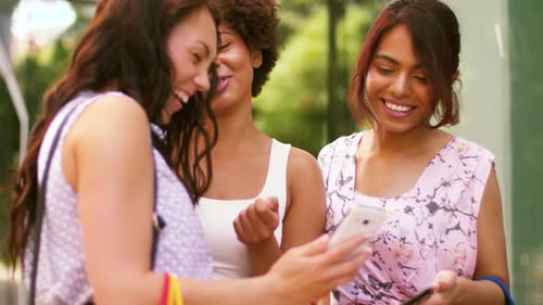 Three Smiling Women Looking at a Mobile Phone