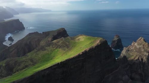 Drone shot of a dramatic slope on a cliff at the coast of Madeira during a sunny day.