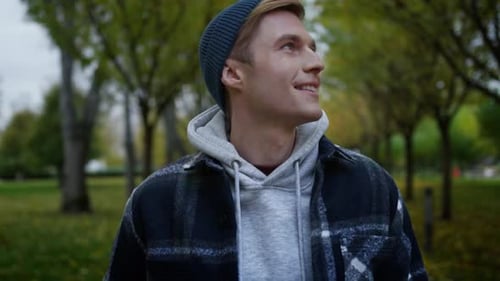 Handsome young man enjoys a beautiful autumn day walking through central park