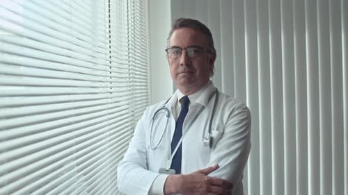 Doctor in White Coat Standing Near a Window