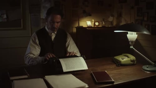 Writer finishing page on typewriter in dimly lit office