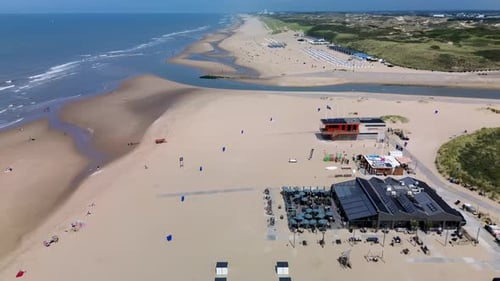 A beautiful aerial view of a sandy beach with rows of beach huts, people relaxing by the shore