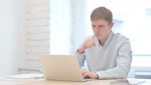 Young Adult Working on Laptop in Bright Office