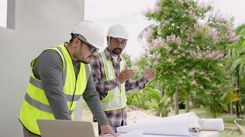 Workers discuss plan in on-site construction. Asian engineers in yellow vests and white safety helme