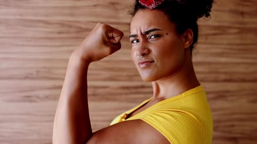 Bold African American Lady in Yellow Displaying Power – Muscular Pose and Direct Gaze, Symbol of