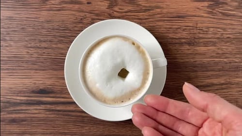 Adding Brown Sugar to Frothy Coffee Cup