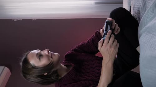 Girl playing in video games with wireless joystick. Vertical video
