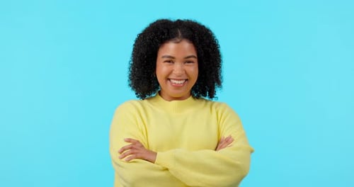 Smile, funny and arms crossed with a black woman on a blue background in studio for comedy or humor