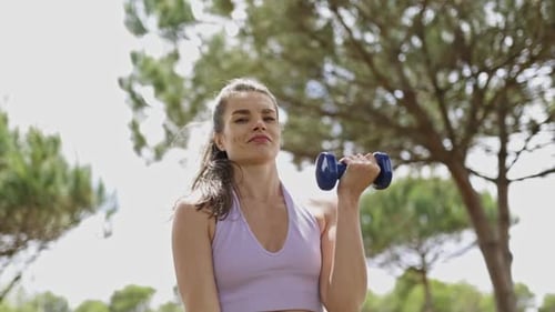 Woman Exercising with Dumbbells in a Park Setting