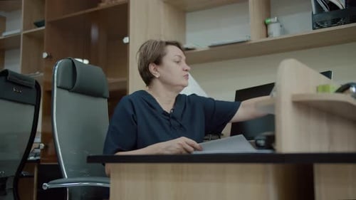 Office Worker Organizing Documents at Desk