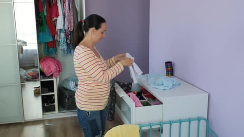 Woman Sorting Children's Clothes in Bedroom