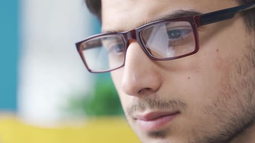 Close-up portrait of serious focused young man with glasses.
