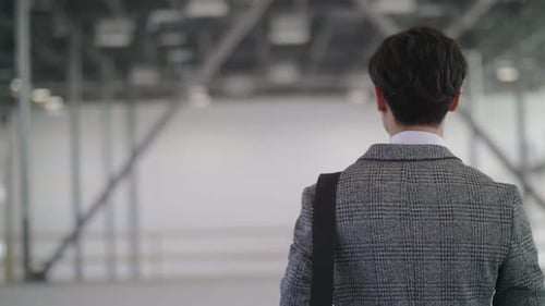 Mature asian businessman walks through vacant warehouse inspecting property