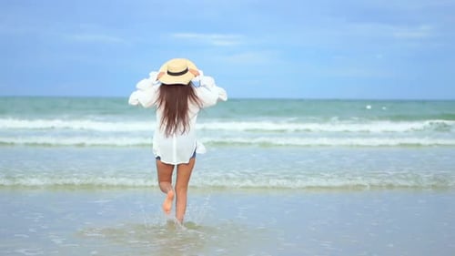 With her back to the camera, a healthy fit young woman runs into the incoming waves. Copy space