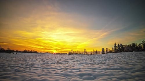 Zeitrafferaufnahme einer schneebedeckten ländlichen Landschaft mit aufgehender Sonne im Hintergrund über gelbem Himmel dur