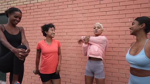 Multi ethnic group of athletes stretching arms before starting their workout in the city, promoting