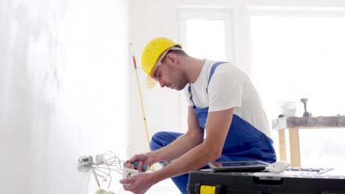 Electrician installing socket using screwdriver in bright room