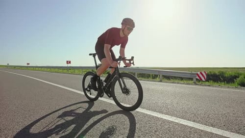 Cyclist Riding Bike on Country Road, Daytime