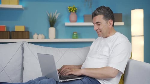 Man Using Laptop on Sofa at Home