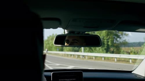 Der Fahrer hinter dem Steuer eines Luxusautos fährt die Autobahn entlang und schaut in den Rückspiegel
