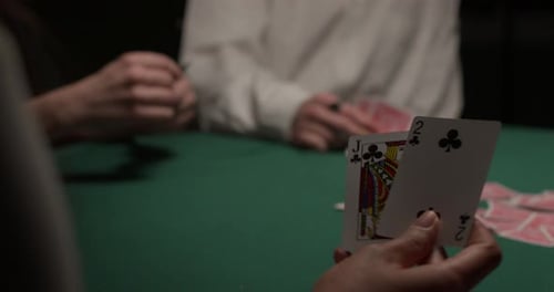 Une joueuse pioche deux cartes puis les remet dans un casino sombre et maussade